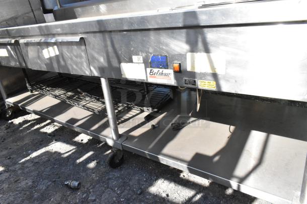 Belshaw stainless steel commercial prep station with over shelf, drawers, under shelf, and casters. Features visible labels.