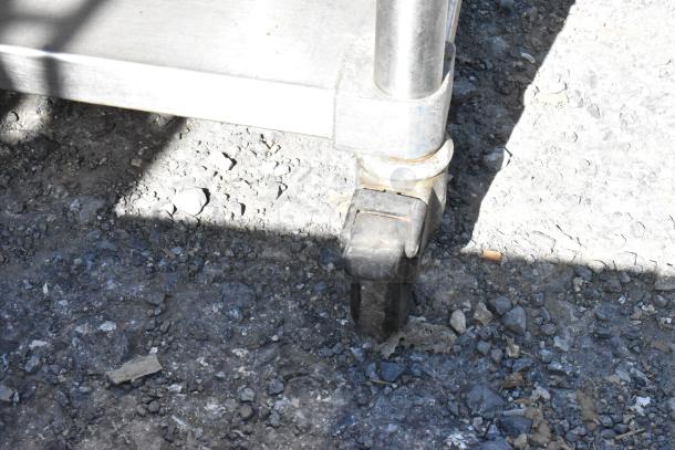 Belshaw stainless steel prep station caster, showing durable wheel design on rough terrain, highlighting mobility feature.
