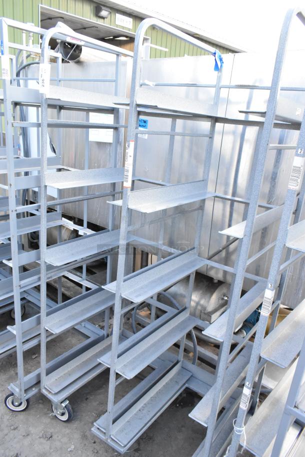 2 metal double transport racks on commercial casters, showing sturdy construction and signs of outdoor use.