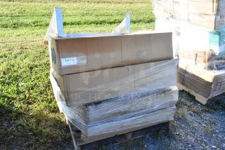 Stacked boxes of scratch and dent items on a pallet, including a stainless steel wall shelf. Boxes partially wrapped in plastic.
