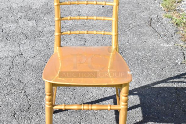 Brand new Lancaster Table & Seating Gold Resin Chiavari Chair with minor scratches and dents, outdoor setting.