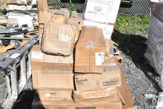 Boxes of new "scratch and dent" items, including stemless wine glasses and square mounts, on a gravel surface.