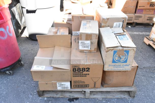 Boxes of assorted brand new dishware, including Libbey and Syracuse China, on a pallet marked as scratch and dent.