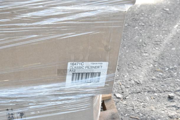 Cardboard box labeled "16471C CLASSIC PILSNER T" with 12 pieces, wrapped in plastic, on a pallet. Scratch and dent condition.