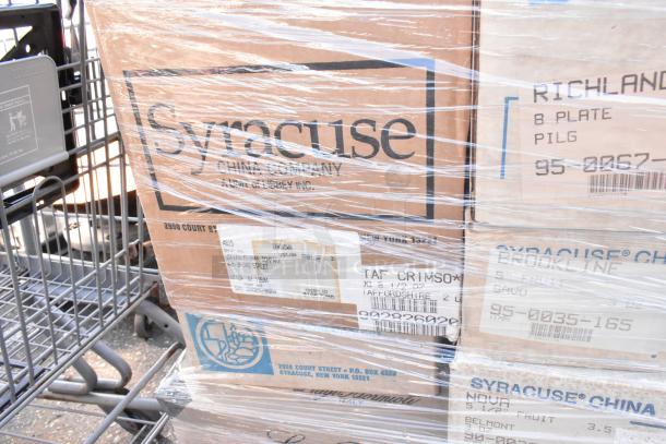 Boxes containing Syracuse China dishware with visible shipping labels, shrink-wrapped on a cart. Scratch and dent condition.