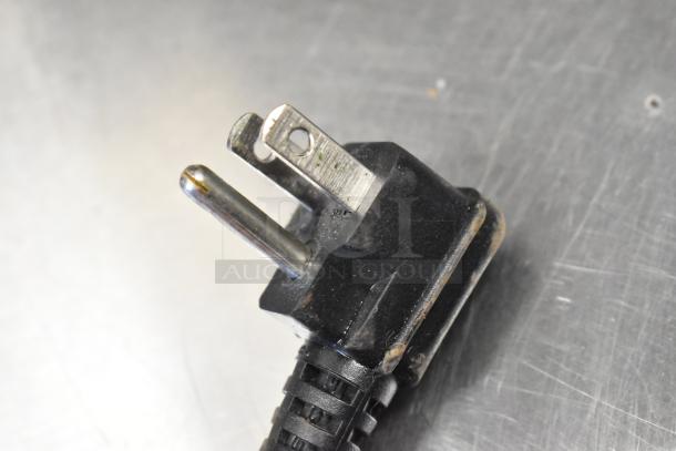 Close-up of a worn power plug, likely from the 2017 Atosa MGF8402GR cooler, showing three prongs and a black plastic casing.