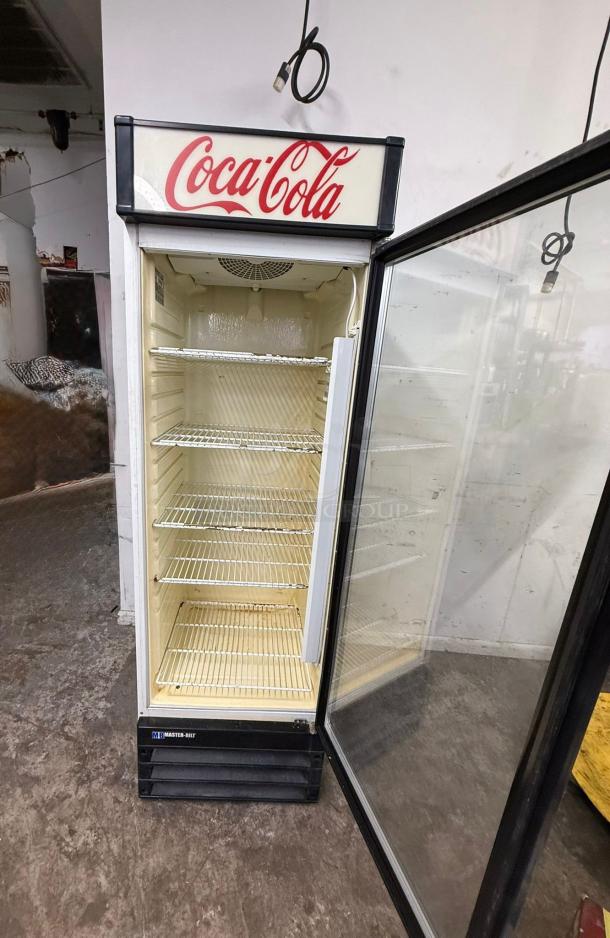 Master-Bilt Coca-Cola commercial cooler merchandiser with single glass door, visible interior shelving, and branding logo.