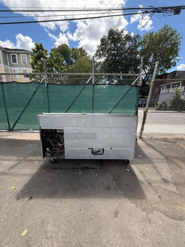Delfield 18672BUCMP 72" undercounter refrigerator, stainless steel, visible wear, outdoor setting, view of rear panel.