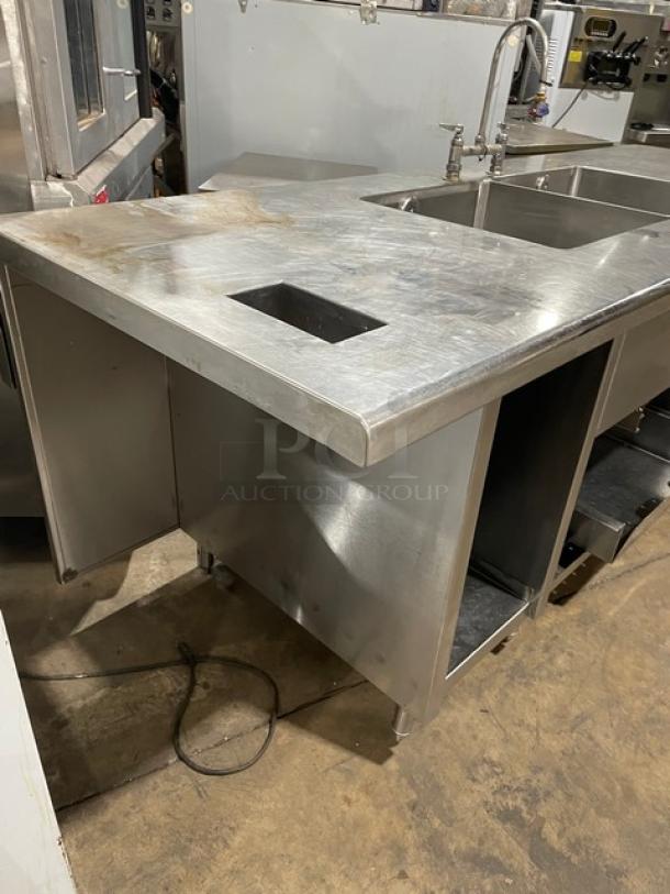 Custom commercial stainless steel double compartment handwashing/prep sink workstation. Features goose neck swivel faucet and enclosed cabinet base on legs. Visible wear on the surface. Perfect for commercial kitchens.