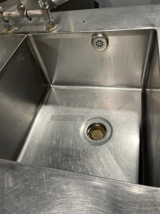 Custom stainless steel double compartment sink with gooseneck swivel faucet, enclosed cabinet base, on legs, slightly worn.