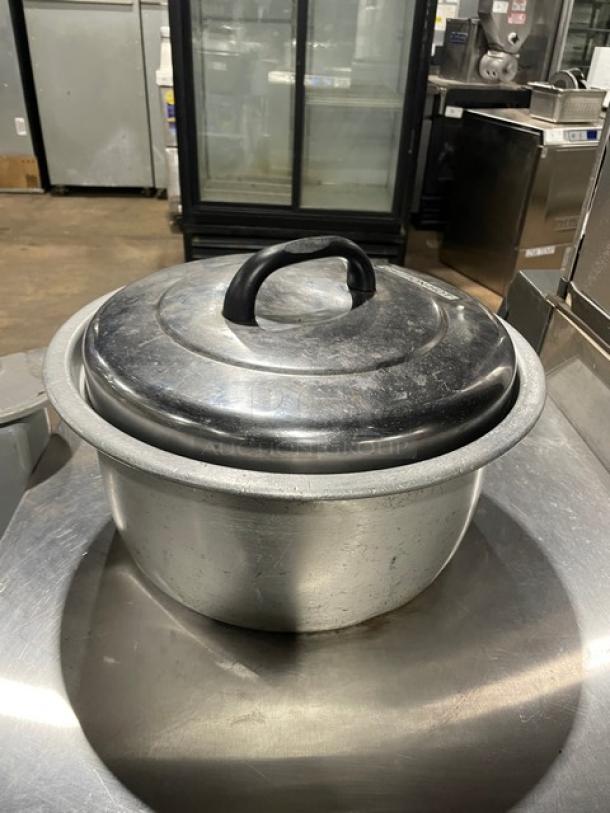 Vintage aluminum rice cooker with cover, commercial-grade, seen in used condition. Features a large handle on the lid.