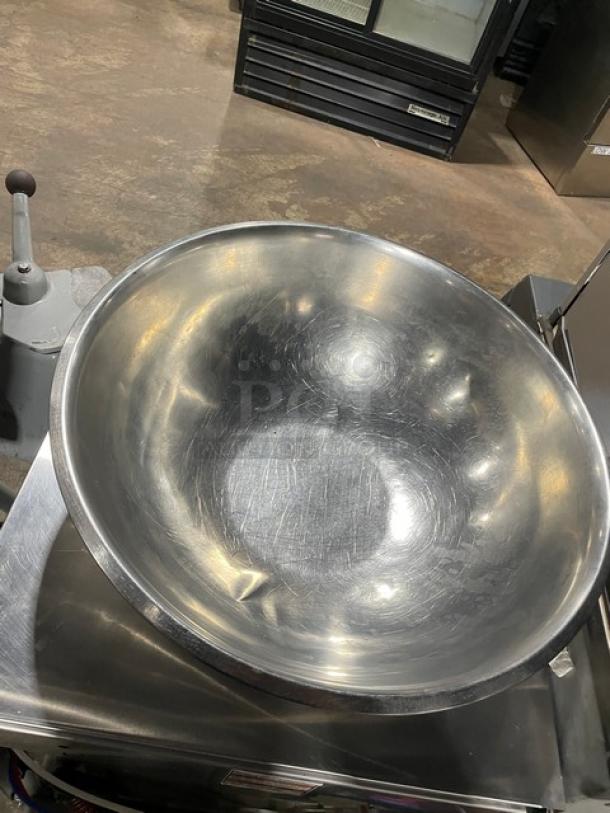 Commercial stainless steel round mixing bowl, large, showing minor scratches, indicative of light wear.