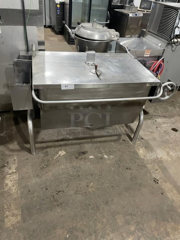Groen stainless steel natural gas tilt skillet on legs, used condition, visible control knobs, and lid handle, model details not visible.