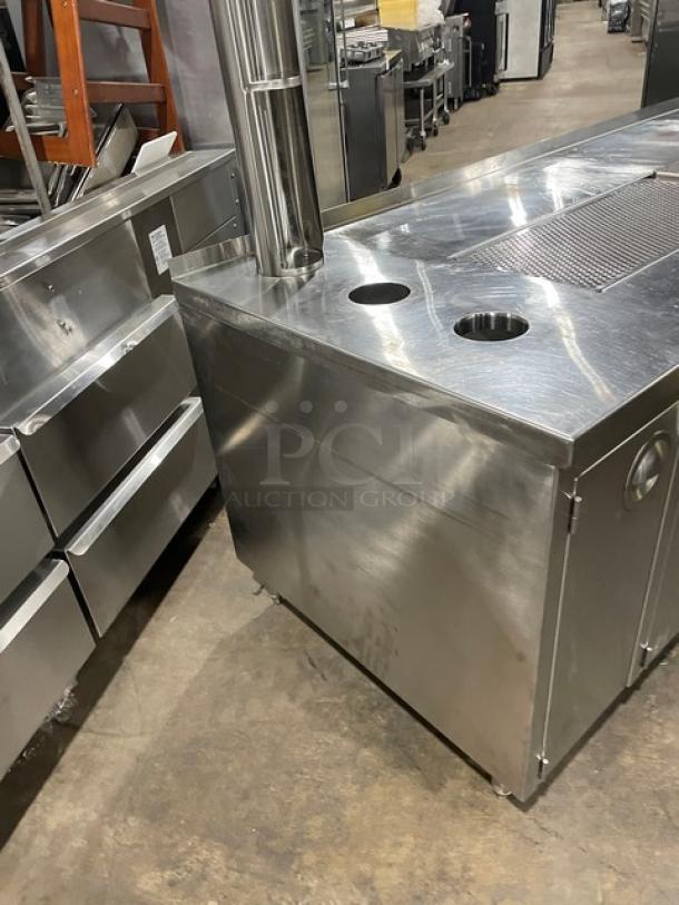 Custom stainless steel beverage dispensing station with double drain boards, enclosed cabinet base, and legs. Commercial-grade.