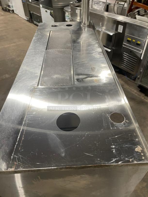 Custom stainless steel beverage dispensing machine work station with double drain boards, enclosed cabinet base, on legs.