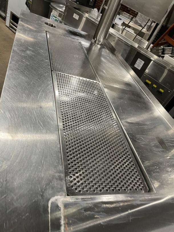 Custom stainless steel beverage station with double drain boards, enclosed cabinet base, on legs. Appears in good condition.