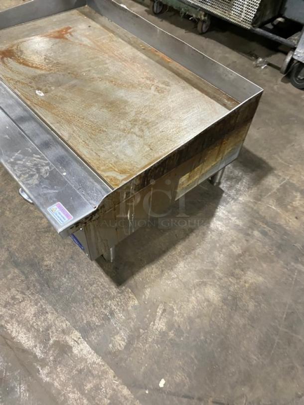 Cook Rite stainless steel natural gas countertop flat griddle with back and side splash, on legs. Visible wear.