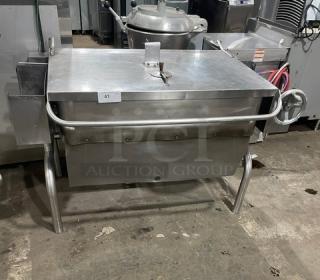 Groen commercial stainless steel natural gas tilt skillet on legs, with handle and lid. Model label indicates natural gas use.