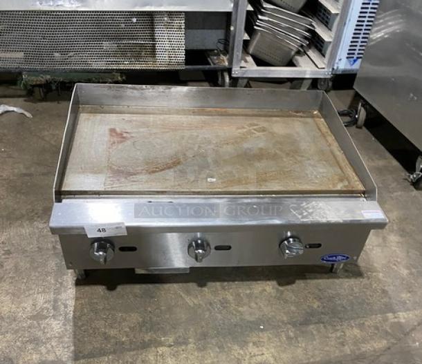 Cook Rite commercial stainless steel natural gas countertop flat griddle with back and side splash, on legs.