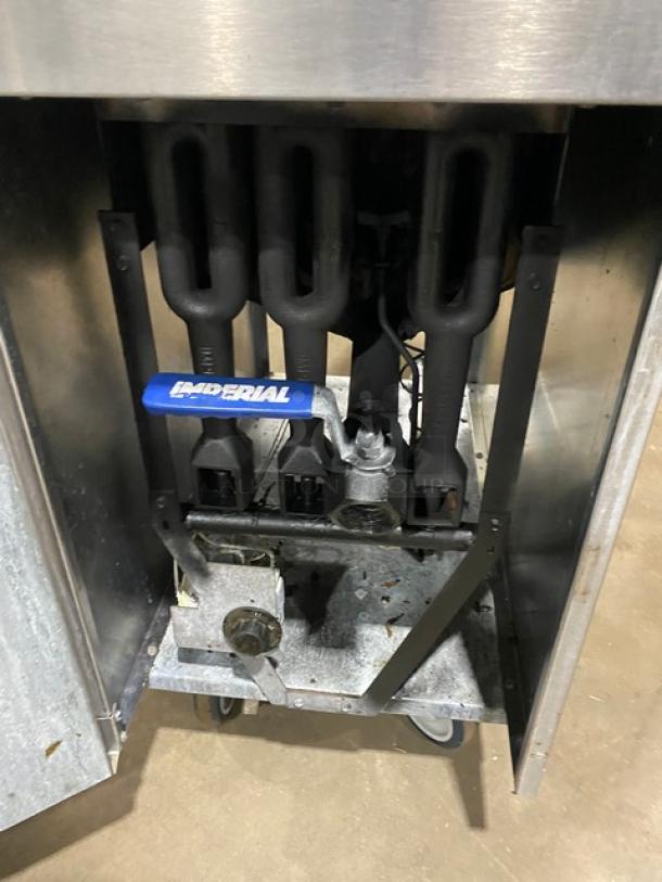 Imperial commercial stainless steel deep fat fryer, natural gas powered, with back splash, basket hanger, and casters.