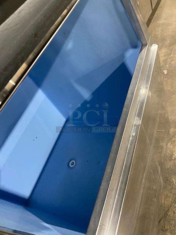 Hoshizaki stainless steel ice maker, model KM-1340MWH. Open bin view, top condensing unit, blue interior, on legs.