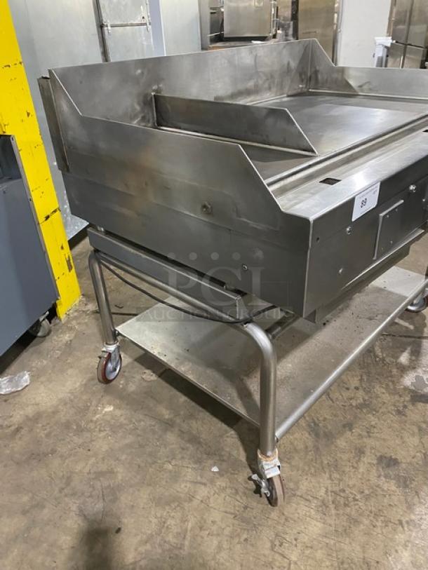 WoodStone stainless steel natural gas countertop plancha flat griddle with back and side splash, on undershelf cart with casters.