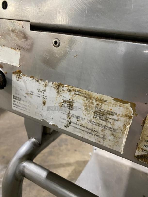 WoodStone stainless steel natural gas countertop plancha flat griddle with back and side splash, on casters, visible wear.