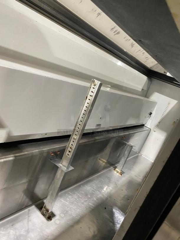 True TSSU-72-18 refrigerated prep table interior; stainless steel, adjustable support rail, well-maintained.