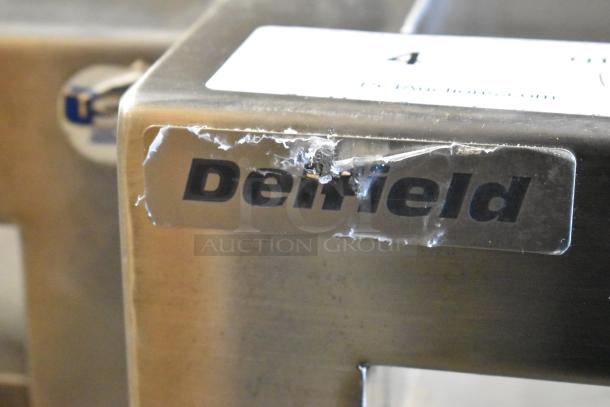 Delfield stainless steel prep table with visible label, commercial casters, and minor wear. 115 volts, 1 phase.