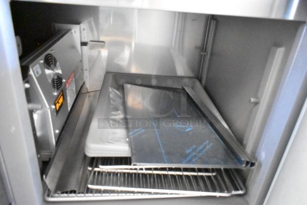 Delfield stainless steel commercial prep table interior, with wiring and cooling unit visible; features shelves and trays.