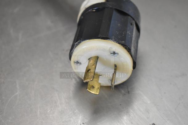 Close-up of the Carpigiani LB100/B batch freezer's electrical plug, showing brass prongs and a black and white casing.