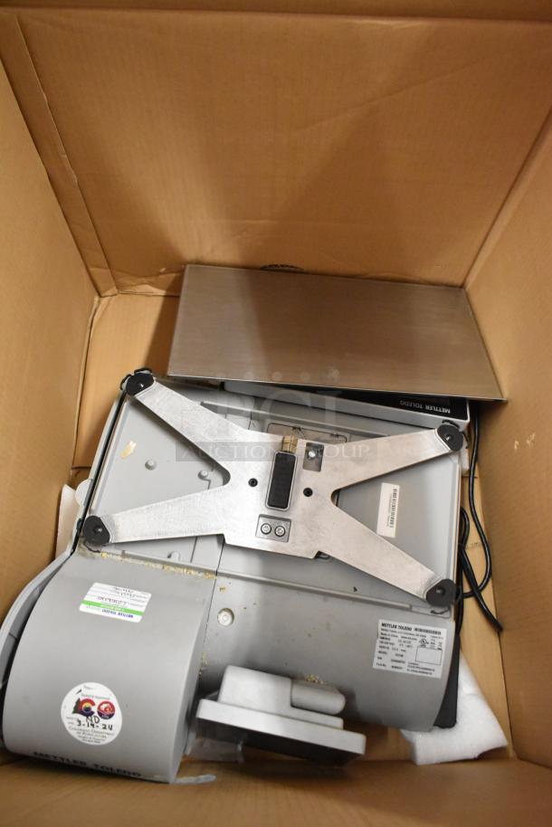 Mettler Toledo UCCW commercial scale in packaging; metal construction, 100-240V, 1 phase, tags show electrical specs.