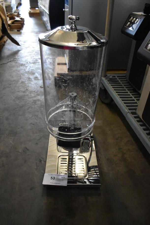 Brand new metal and poly dry dispenser, scratch and dent, clear container, chrome lid and base, auction tag visible.