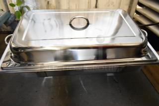 Brand new stainless steel chafer, rectangular with lid, minor scratches and dents visible, ideal for catering.