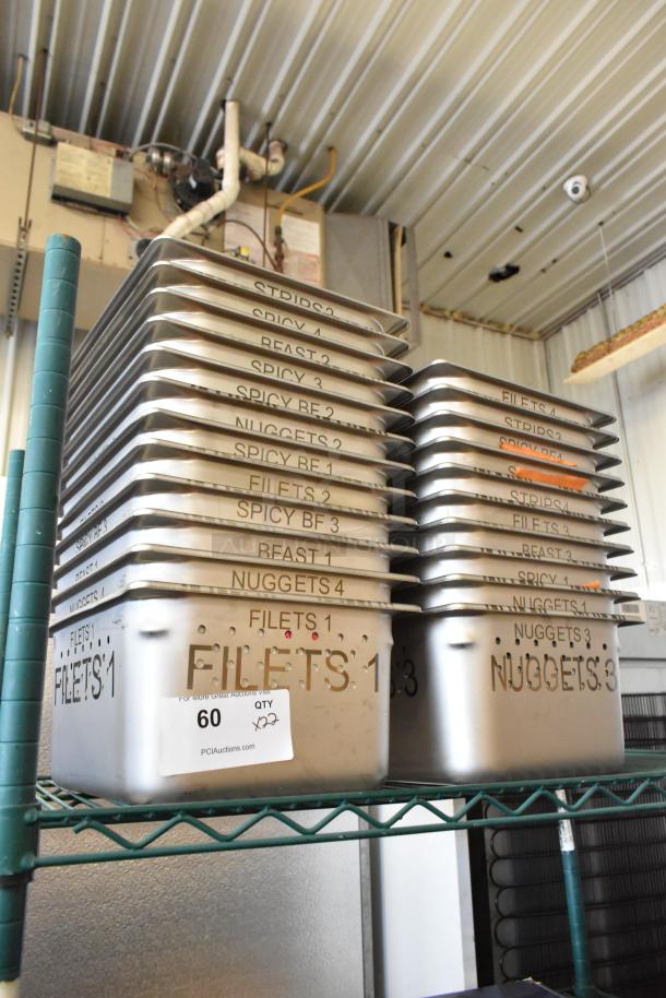 Stack of 22 stainless steel drop-in bins labeled with food names, new with minor scratches, on a metal shelf. Tags indicate auction lot.