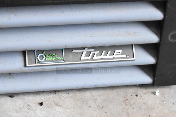 2018 True GDM-12-HC single door merchandiser with poly-coated racks, natural refrigerant label. Model badge visible.