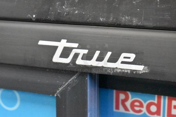 True GDM-41SL-54-HC-LD cooler logo on a black metal surface, showing slight wear.