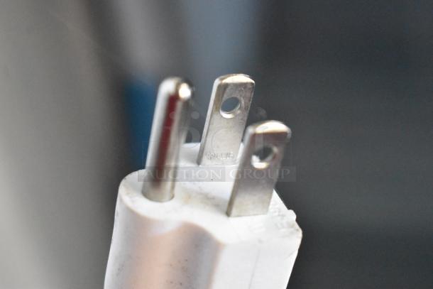Close-up image of a three-pronged electrical plug, possibly from the Accucold ARG3PV cooler, showing the metal prongs.
