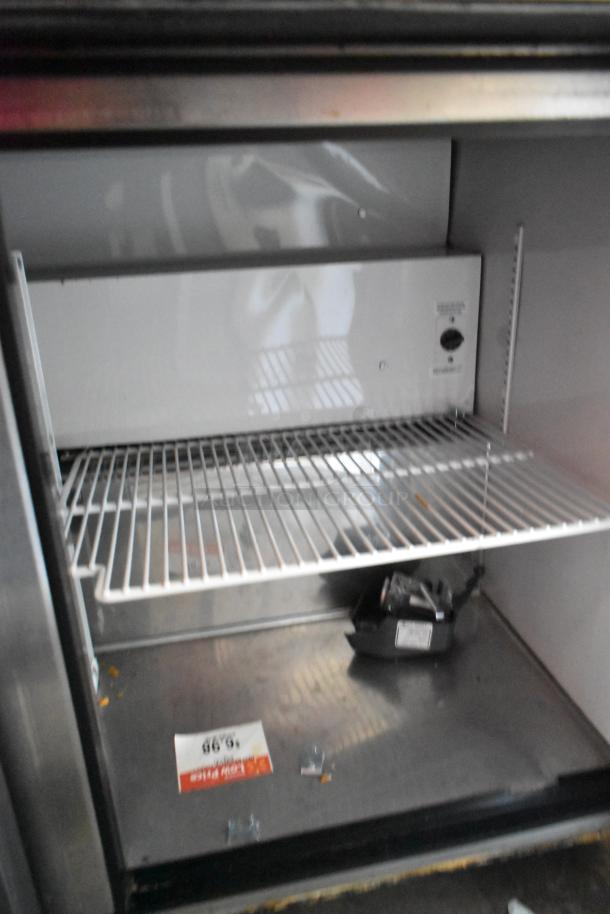 True TWT-72 stainless steel pizza prep table interior with shelves and visible pricing label. Commercial-grade, 115 volts.