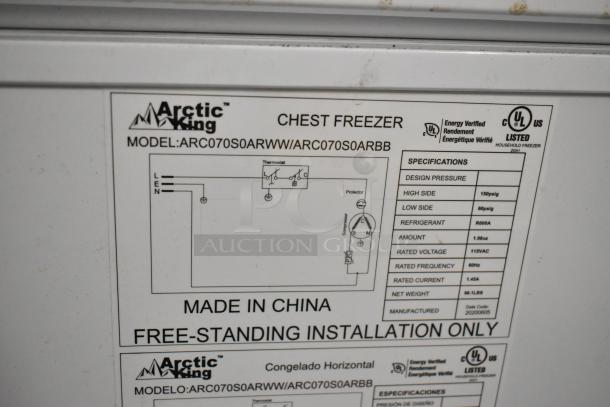 Arctic King ARC070S0aRWW metal chest freezer with hinge lid. Features specifications label detailing voltage, refrigerant, and design.
