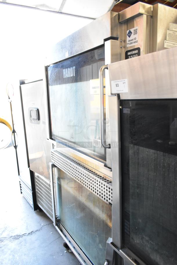 Two Hardt Inferno 3500 stainless steel rotisserie ovens, natural gas powered, 40 bird capacity each, on commercial casters.