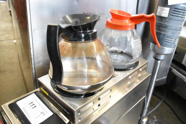 Bunn CWTF15 stainless steel 3-burner coffee machine with hot water dispenser, metal brew basket, and two coffee pots visible.