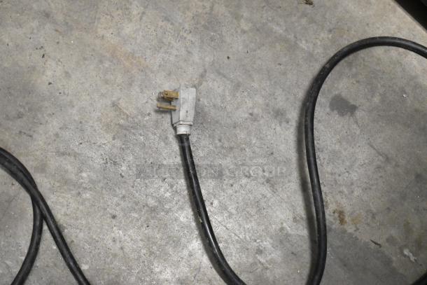 A power cord on a concrete floor, possibly for the True GDM-37-LD cooler, showing standard plug.