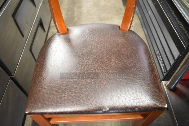 Wooden dining chair with brown seat cushion, used condition. 50 available for auction. Textured surface, wooden frame.