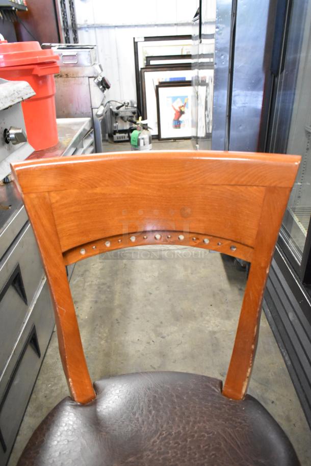 50 wooden dining chairs with brown seat cushions, prominent backrest design, sturdy construction, lightly used condition.