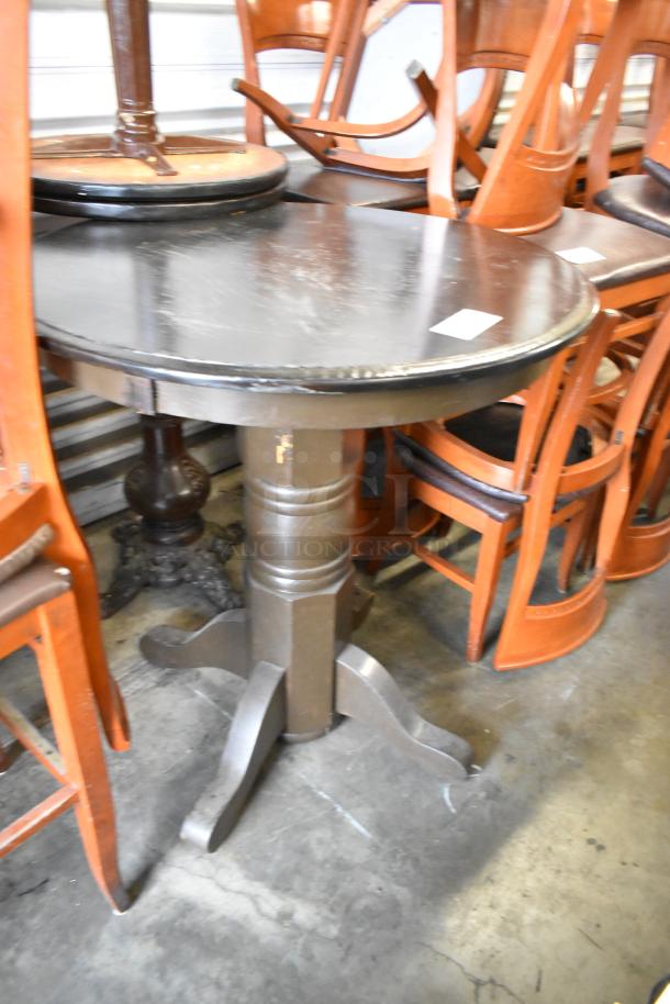 Three wooden tables with round tabletops, sturdy pedestal bases, moderate wear, suitable for home or business use.