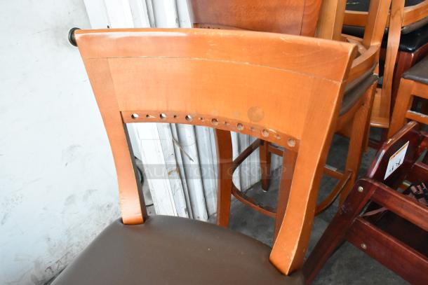 20 Items: 18 bar-height wooden chairs with brown cushions and 2 high chairs. Moderate wear, sturdy construction.