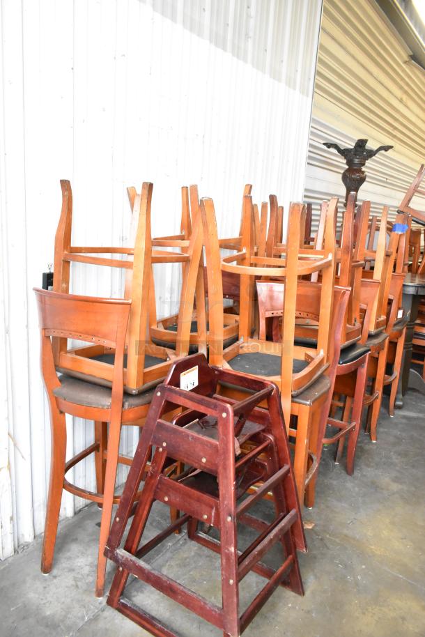 20 wooden bar-height chairs with brown seat cushions and 2 wooden high chairs, good condition, stacked in storage.