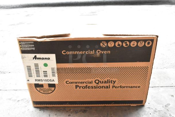 Brand new Amana RMS10DSA stainless steel commercial microwave in crate, 2021 model, dial controls, barcode visible.