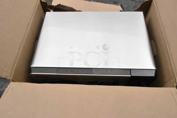 Brand new Amana RMS10DSA stainless steel commercial microwave in crate, featuring dial controls. Model 2021.